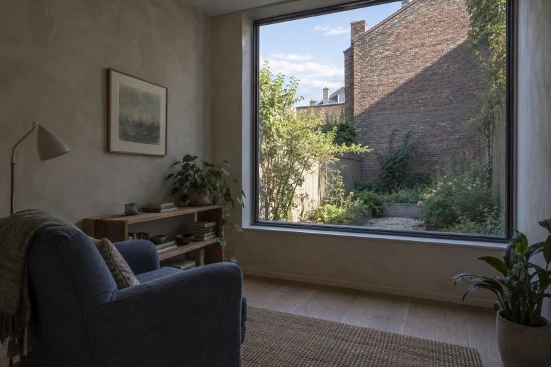 A garden-facing sitting room looks toward a small yard partly shaded by a neighboring brick wall.